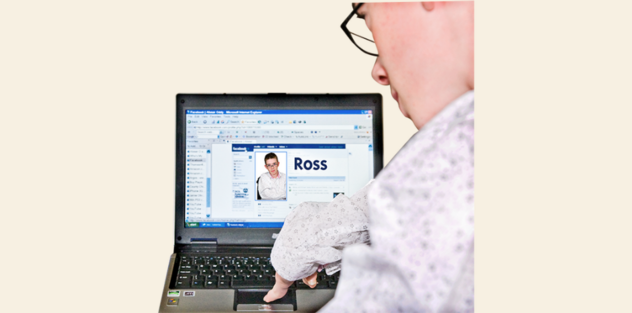 A man typing on a laptop which is showing his online profile page