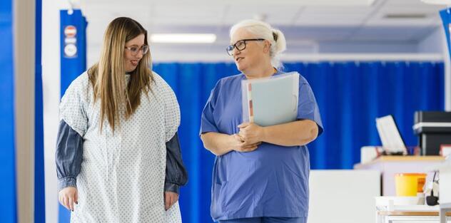 A patient and a doctor walking through a hospital ward talking